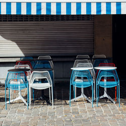 Chairs and tables on sidewalk against building