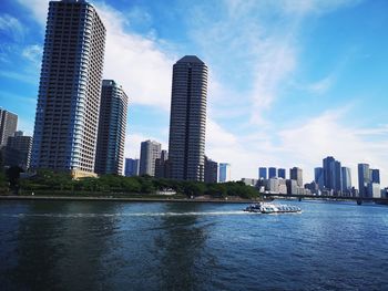 Sea by modern buildings against sky in city