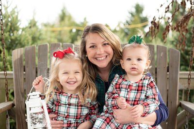 Portrait of happy mother sitting with kids outdoors