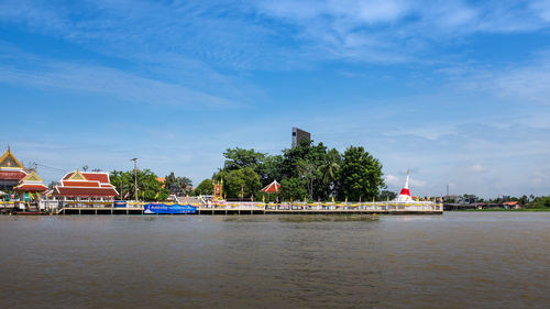 Scenic view of river by buildings against blue sky