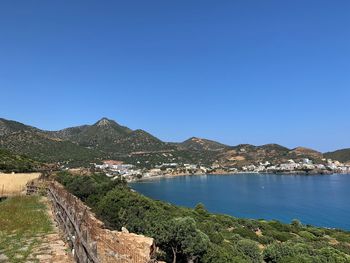 Scenic view of sea and mountains against clear blue sky