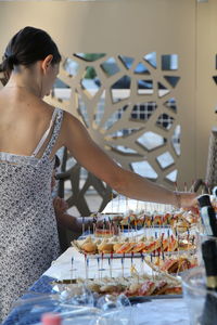 Rear view of woman arranging food on table