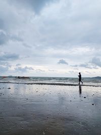 Man walking on beach against sky