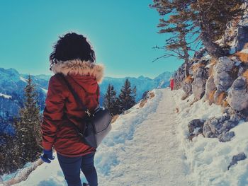 Rear view of woman standing on snow against sky