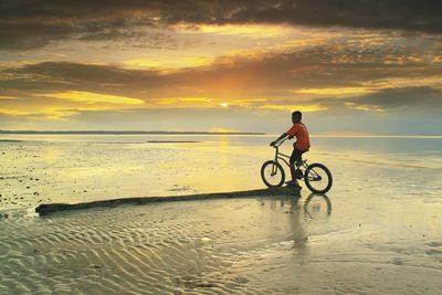 Man on beach against sky during sunset