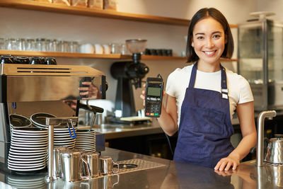 Portrait of young woman using mobile phone in cafe