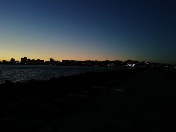 Silhouette city against clear sky during sunset