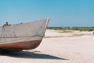 Boat moored on beach against clear sky