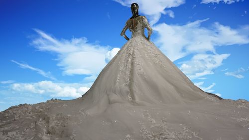 Low angle view of statue wearing wedding dress against cloudy sky