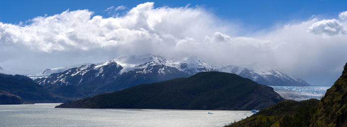 Panoramic view of snowcapped mountains by sea against sky