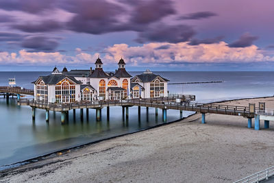 Built structure on pier by sea against sky during sunset