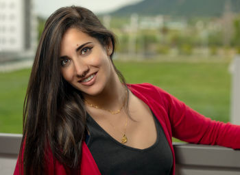 Portrait of beautiful young woman standing by railing