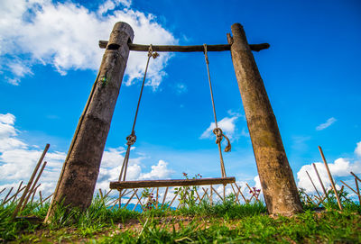 Low angle view of wooden post on field against sky