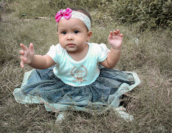 Portrait of cute baby girl sitting on land