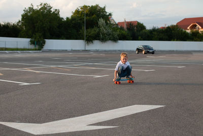 Rear view of boy playing on road