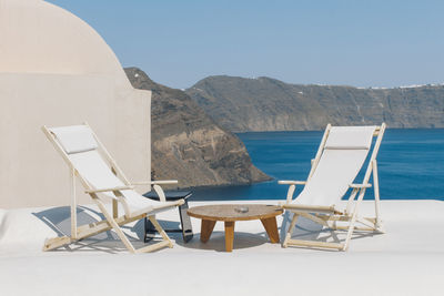 Deck chairs on beach against clear sky