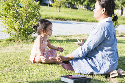 Side view of mother and daughter on field