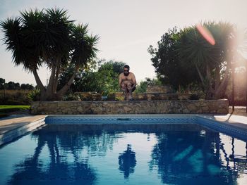 Full length of shirtless man jumping in swimming pool