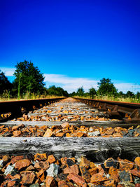 Surface level of railroad track against clear blue sky