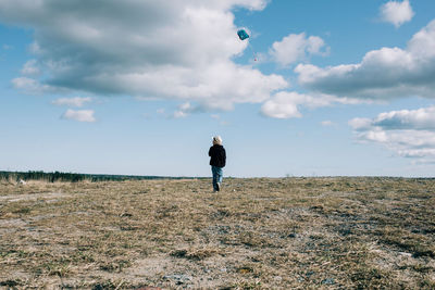 Rear view of man standing on field against sky