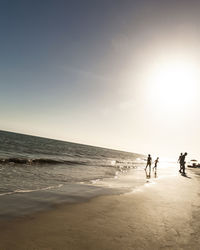 People walking on beach against sky