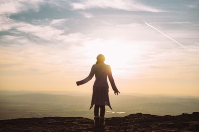 Woman standing on mountain against sky during sunset