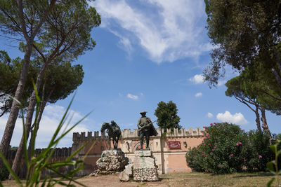 Statue against trees and plants against sky