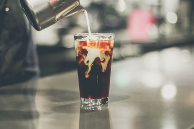 Close-up of hand pouring milk in coffee