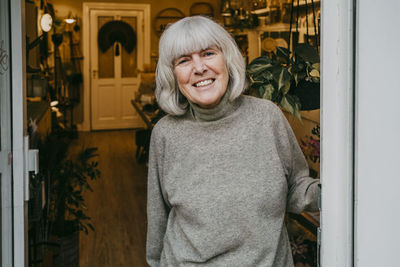 Portrait of smiling senior female owner with gray hair at store doorway