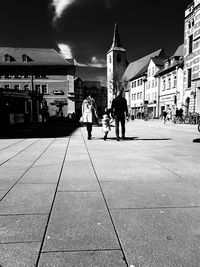 Rear view of people walking on street against buildings in city