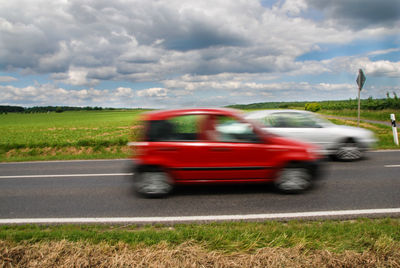Blurred motion of car on road against cloudy sky