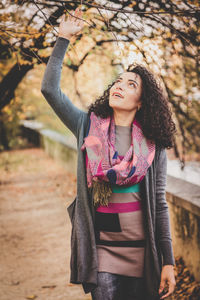 Young woman standing against tree