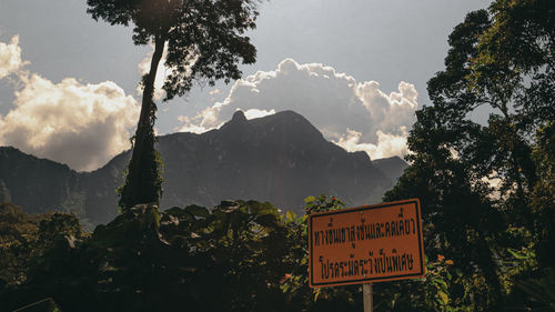 Information sign against trees and mountains against sky