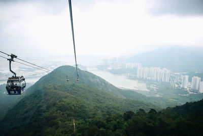 Overhead cable car over mountains against sky