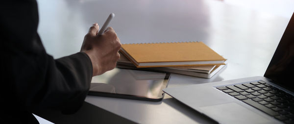 Midsection of man using mobile phone on table