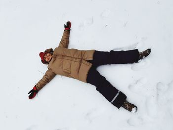 High angle view of child lying on snow covered field