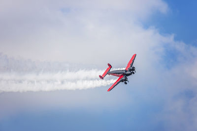 Low angle view of military airplane performing airshow against sky