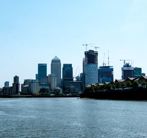 River by buildings against clear sky in city