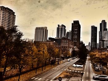 City street by modern buildings against sky