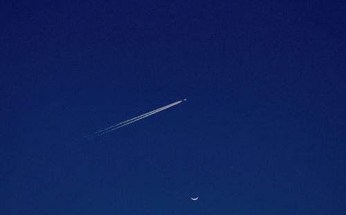 Low angle view of vapor trails in blue sky