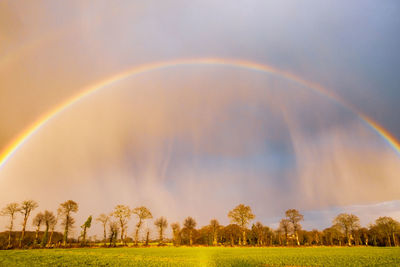 Rural landscape with rainbow over dark stormy sky in a countryside in brittany