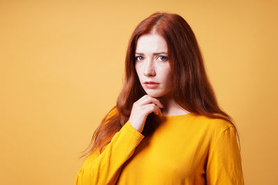 Portrait of young woman against yellow background