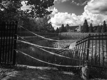 Fence on field against cloudy sky