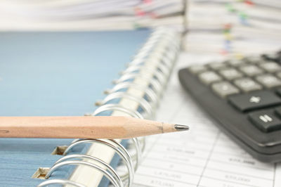 Close-up of pencil on book by calculator on table in office