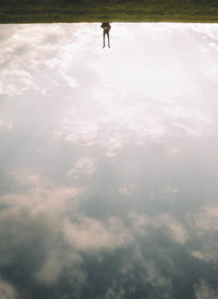 Person upside down on land against sky