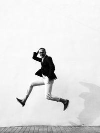 Side view of young man jumping against wall