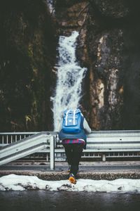 Rear view of person at observation point against waterfall on mountain