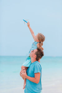Woman with son on beach against sky