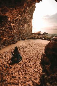 High angle view of woman holding scarf at beach against sky during sunset