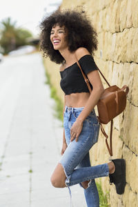 Smiling woman standing against stone wall